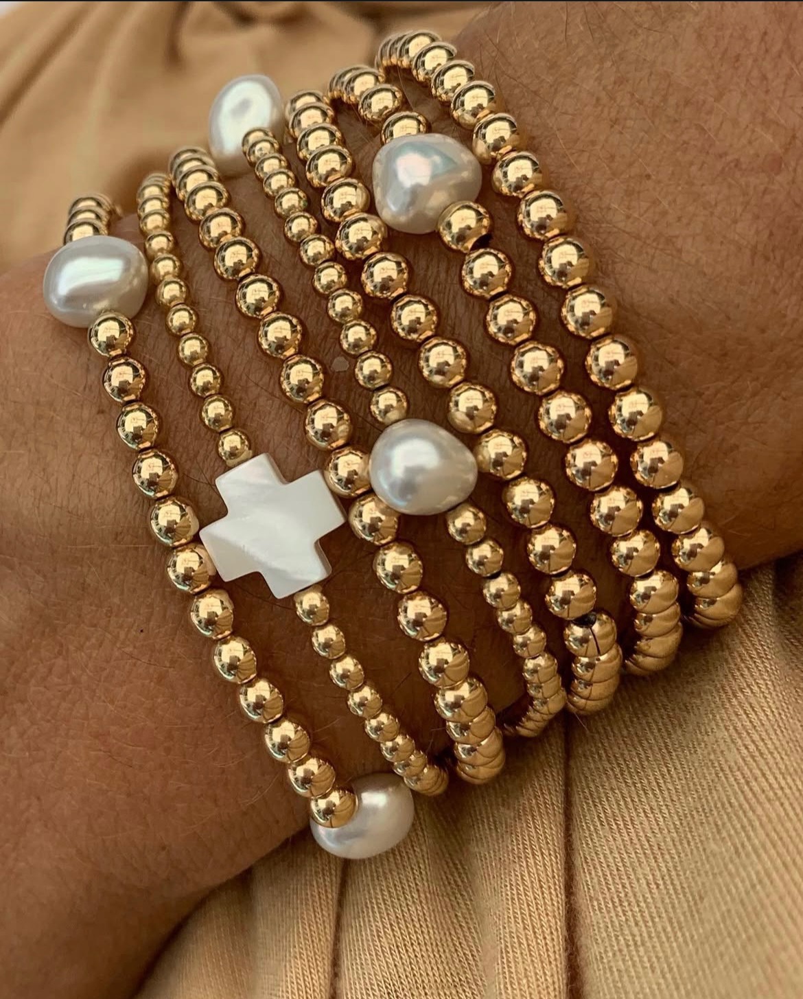 Bracelets category image showing layered gold bracelets with pearls and crosses