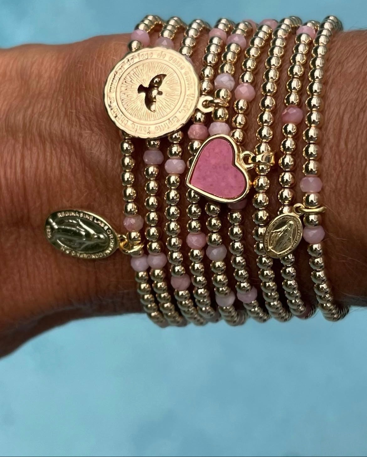 Gold and pink beaded bracelets stacked on a wrist