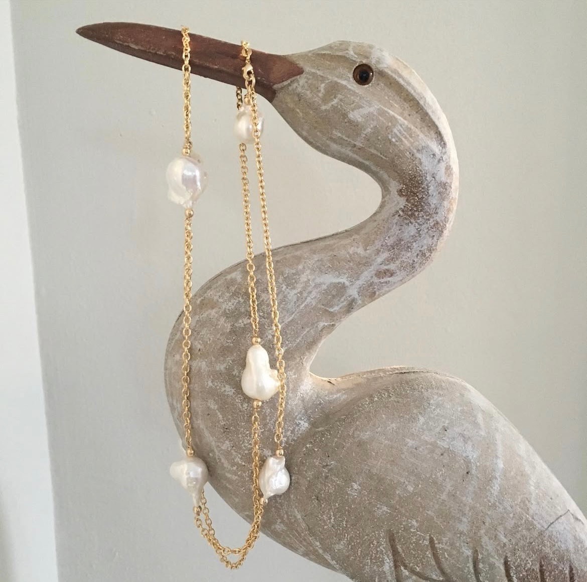 Pearl necklace draped artfully over a carved wooden bird